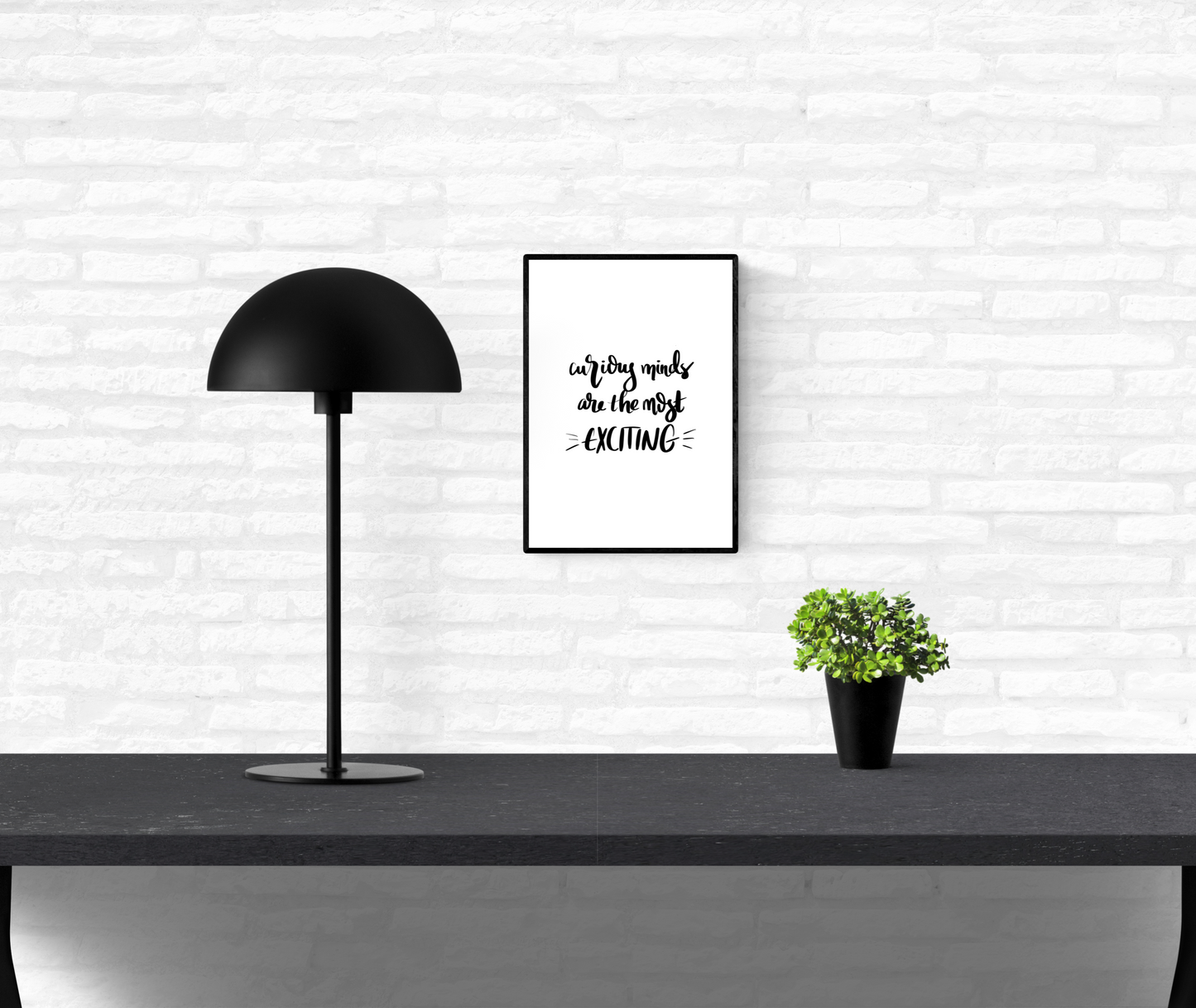 Framed wall quote print with the words, “curious minds are the most exciting”, mounted on an interior white brick wall.