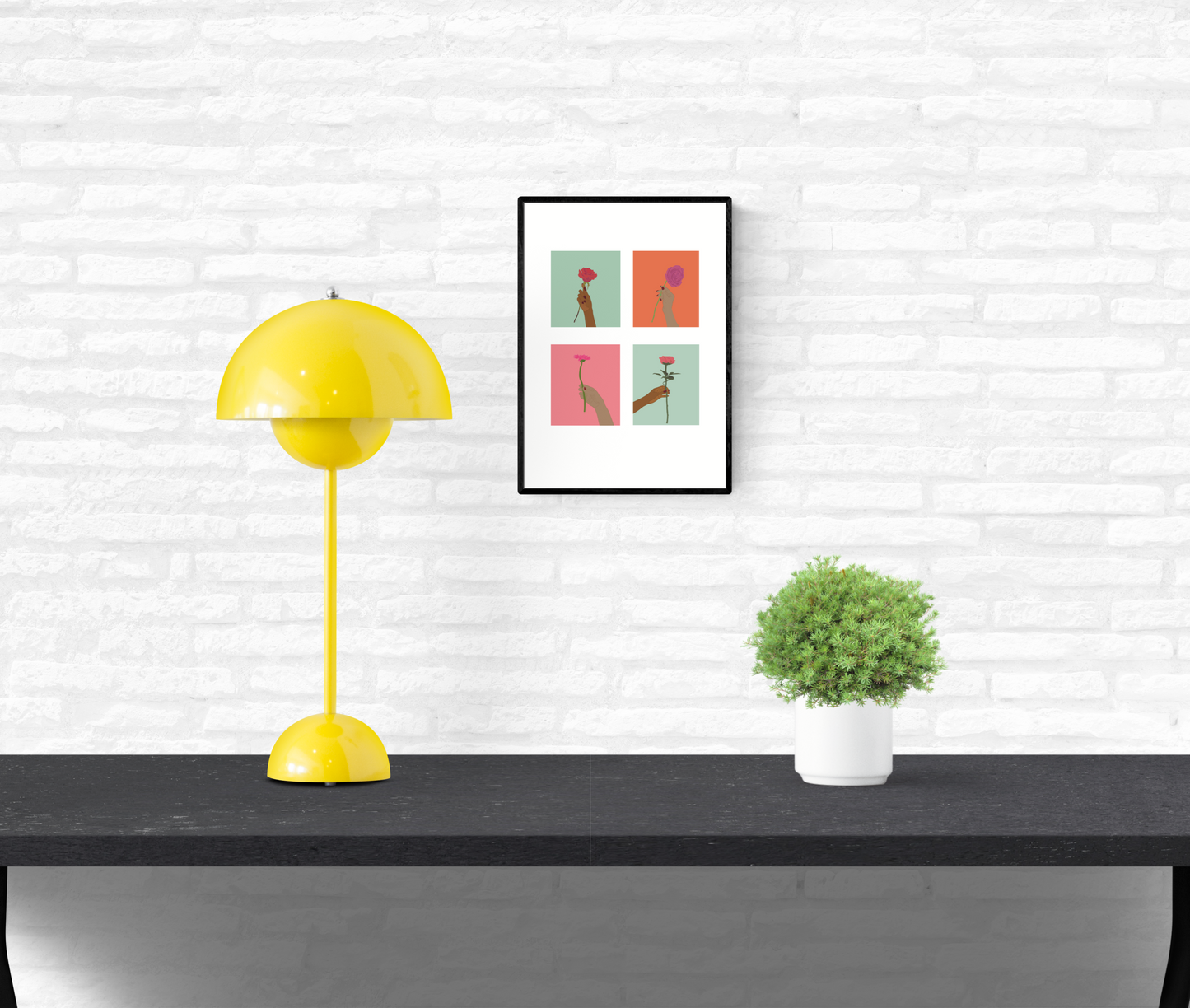 Wall art that is framed and mounted on a home’s interior white brick wall of four hands holding flowers of different colours