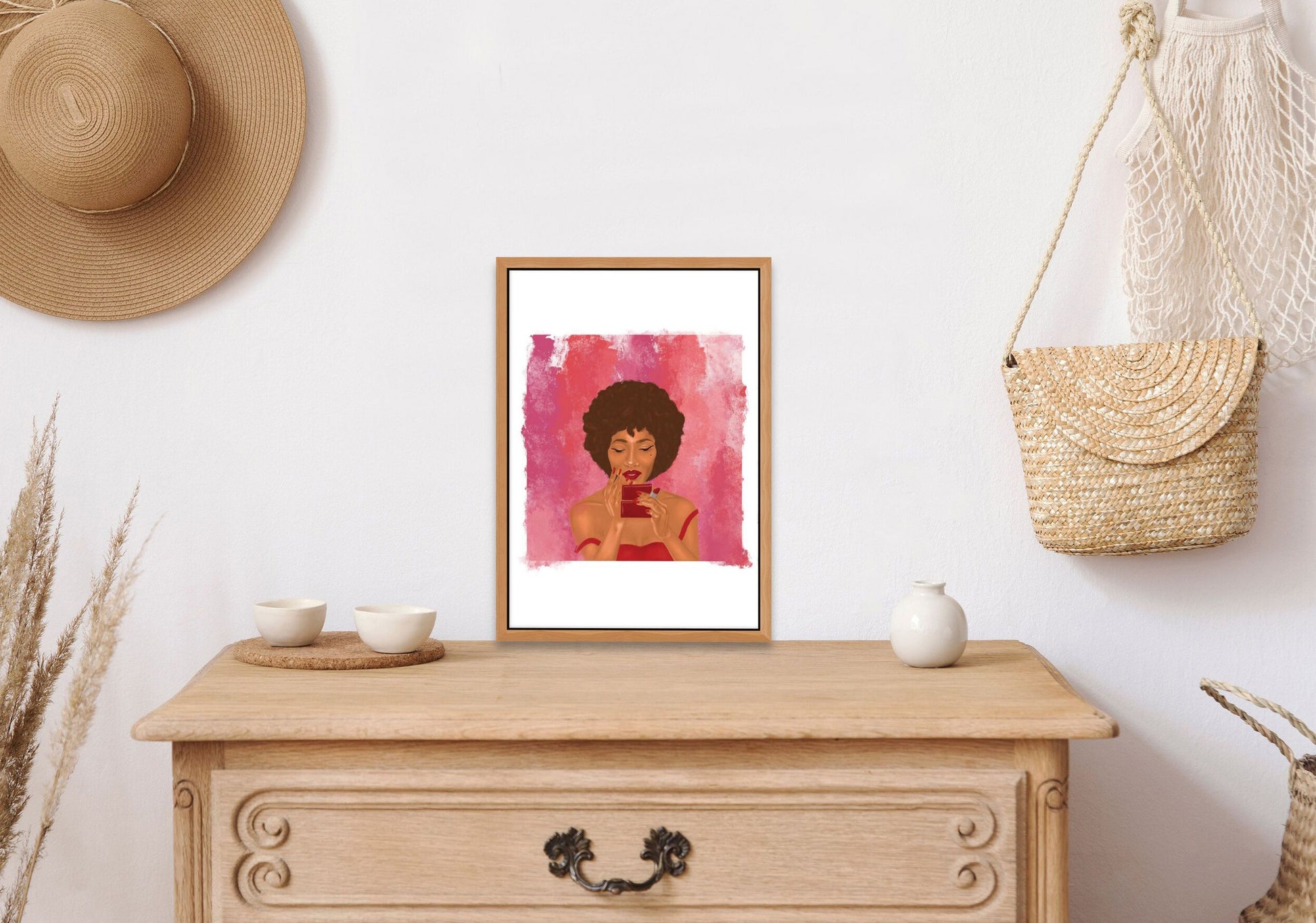 Wall print of an African American woman wearing lipstick sitting on top of a chest of drawers