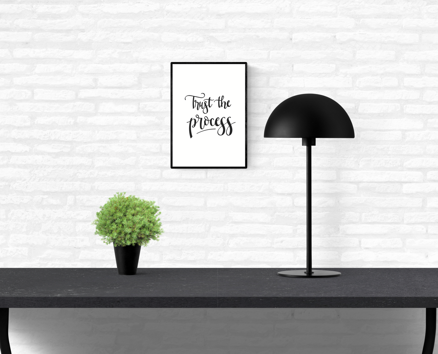 A white, brick home dining room wall with a hung, framed quote print with the words, “Trust the process”
